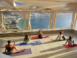 A bunch of woman doing yoga inside a room with glass all around