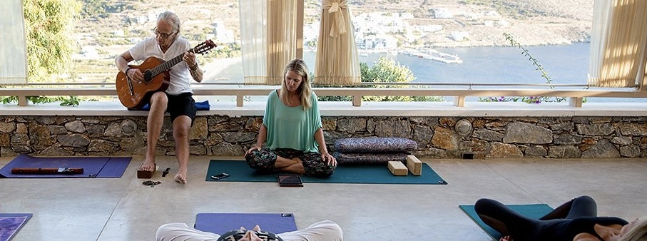 An elder man playing guitar and a woman doing yoga